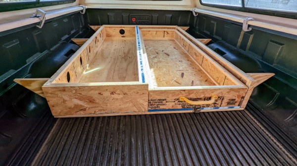 Put the drawer in the base of the bed platform of the truck topper camper. 
