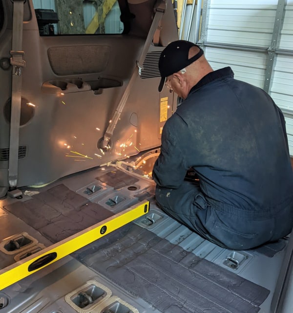 Removing metal brackets from the van's floor. 