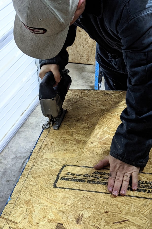 Using a jigsaw to cut the curve of what will become the trunk lid of the van's subfloor. 