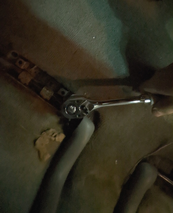Removing the bolt holding in the back seats in a Toyota minivan. 