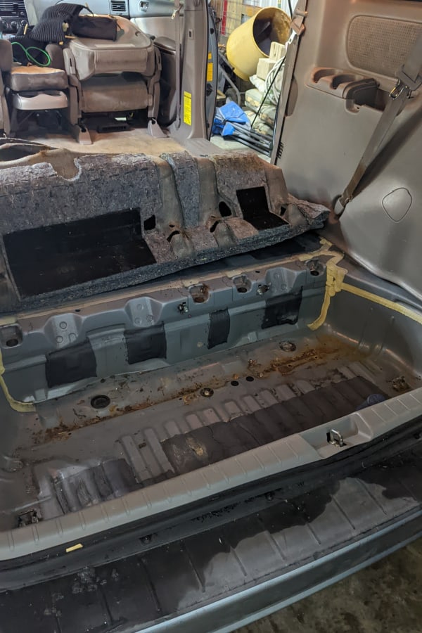 The trunk carpet was removed in preparation for creating a level floor to create a campervan and cargo van out of a minivan. 