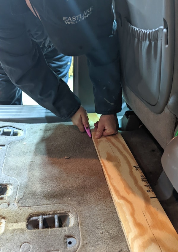 Cutting the carpet behind the front seats of the minivan. 