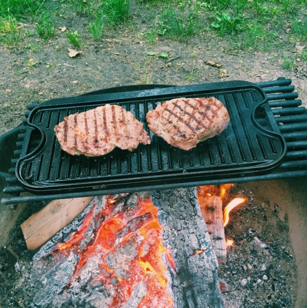 Cooking steaks over the campfire. 